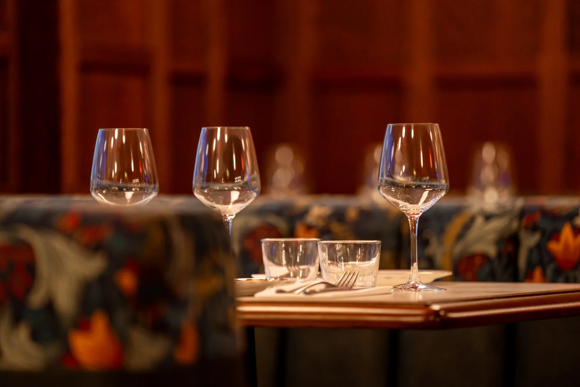 Wine glasses and table settings in a warmly lit dining room.